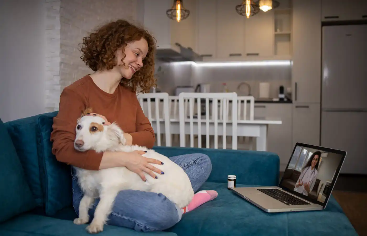 Femme tenant son chien pendant une consultation vétérinaire en ligne sur ordinateur, illustrant les soins vétérinaires à distance et le bien-être animal moderne.